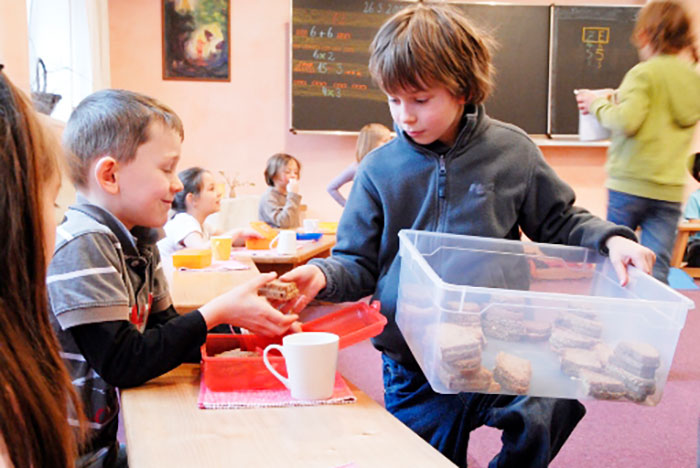 Un enfant distribue les sandwichs du petit-déjeuner dans la classe.